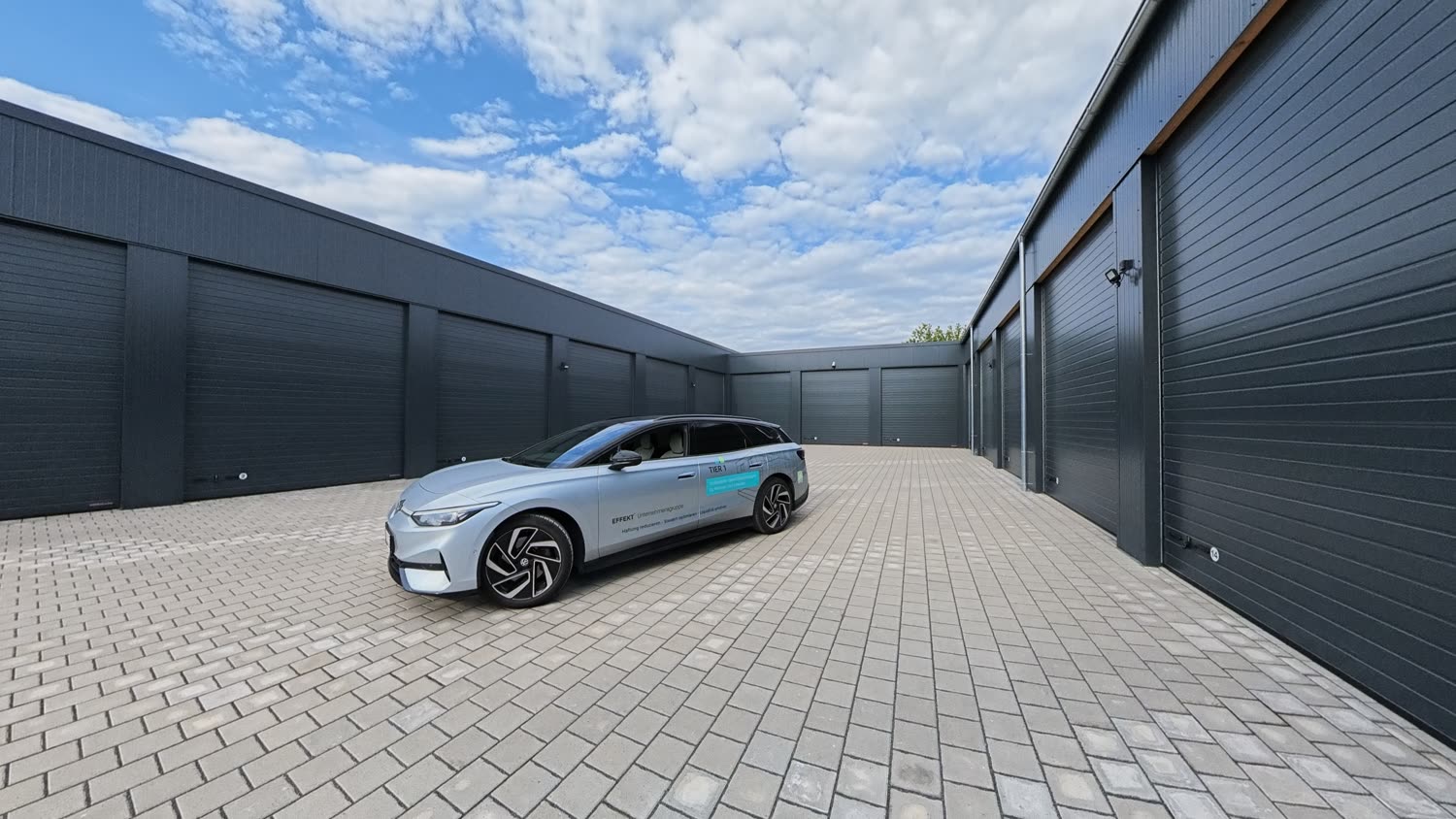 Innenhof des Garagenparks mit Tier-1-Fahrzeug im Abendlicht