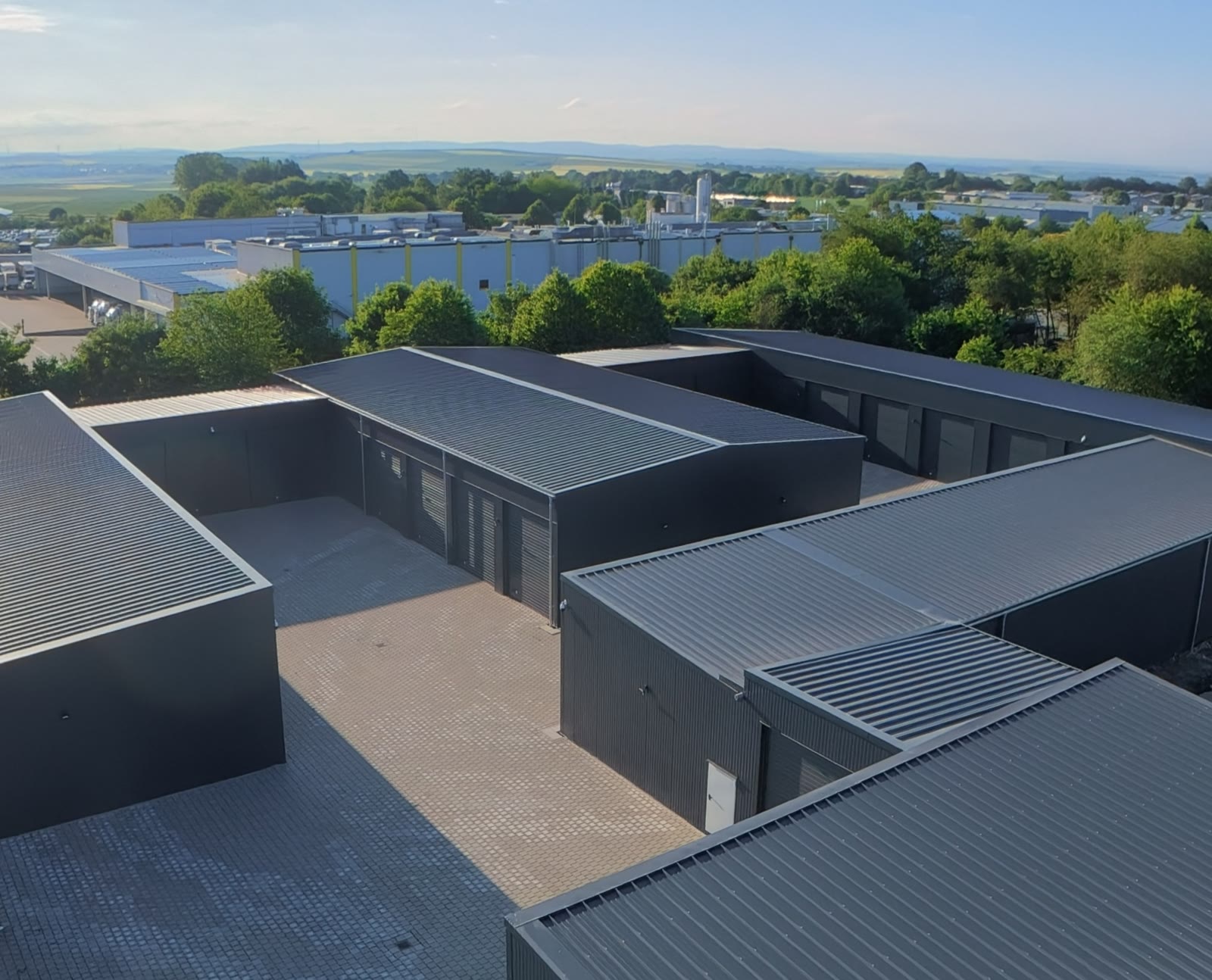 Luftaufnahme über die Dächer des Garagenparks Polch mit Gewerbegebiet Im Gohl und Maifeld am Horizont
